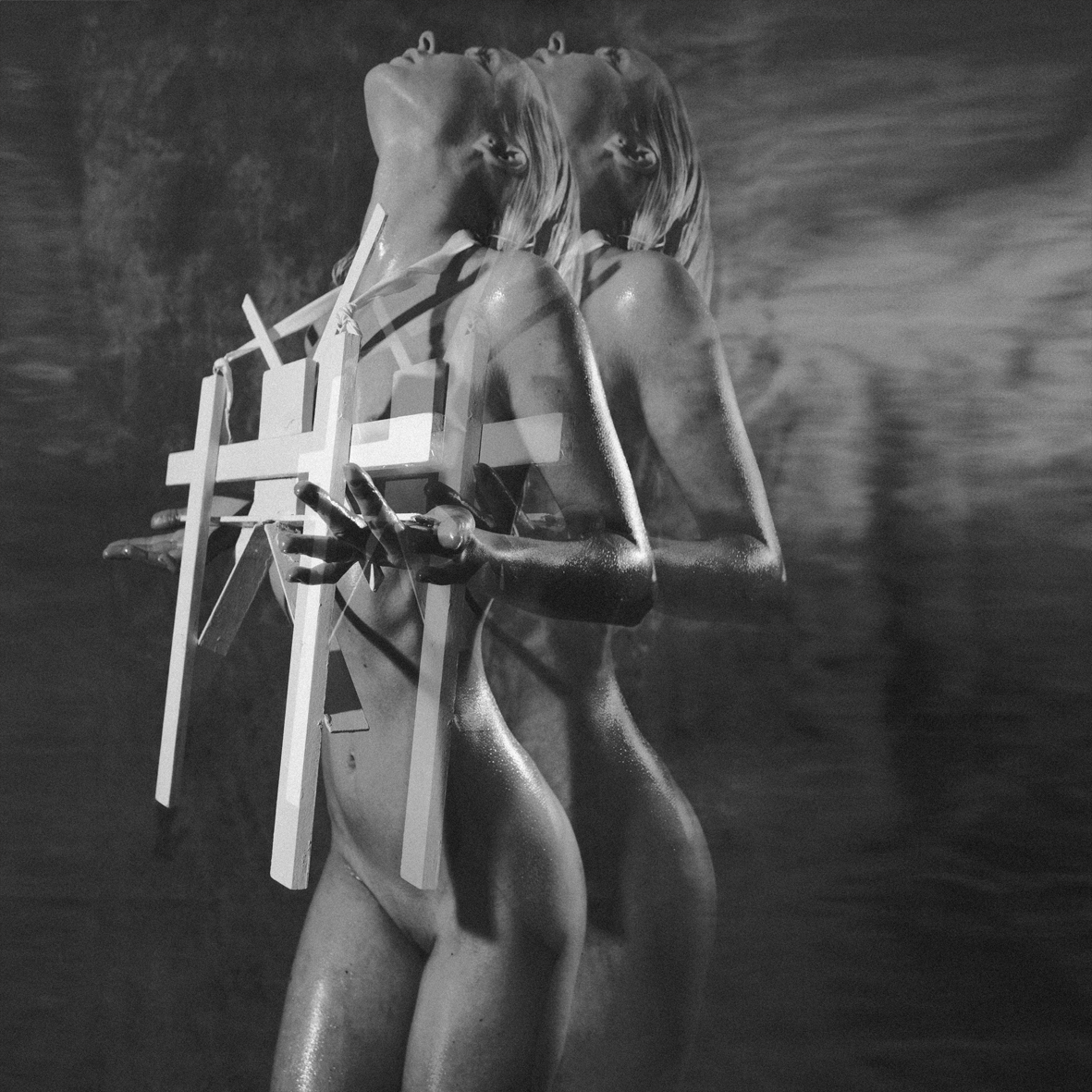 Cross-Bearer — black and white double exposure of two figures embracing a cross structure — Julia Krantz