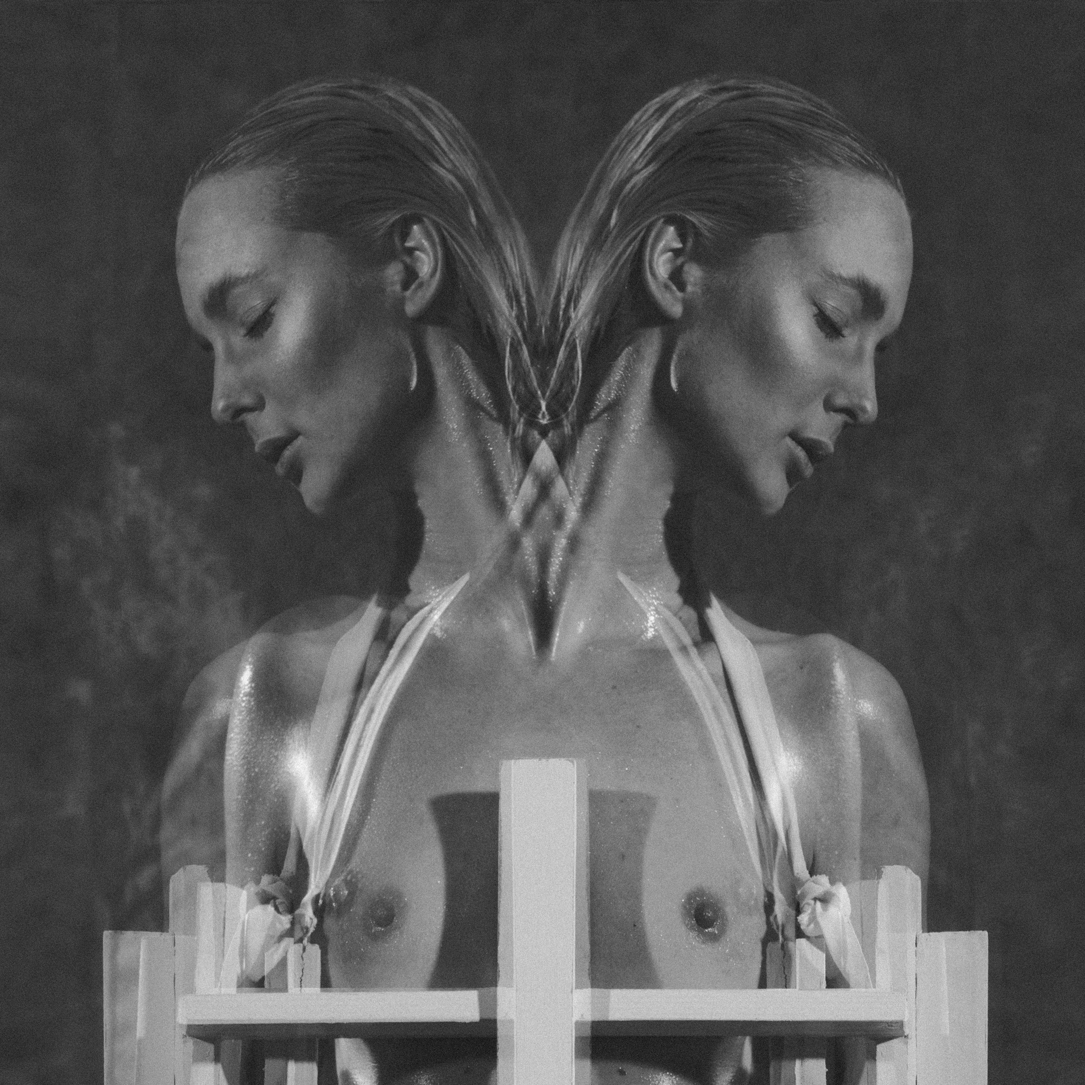 Cross-Bearer — black and white mirrored portrait of two figures with cross harness, eyes closed — Julia Krantz